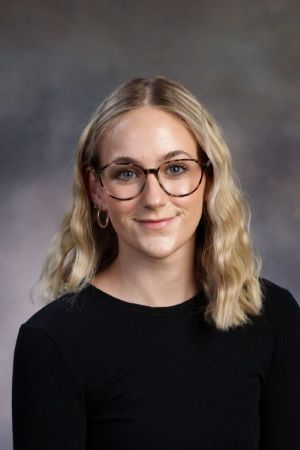 professional headshot of Alexis who is wearing a black shirt and glasses