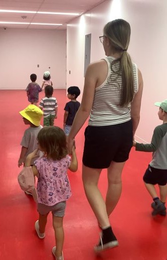 Mackenna holding hands with children as they walk down the hall