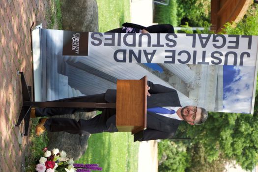 Dr. Mark Harding stands behind a podium with a Justice and Legal Studies banner behind him