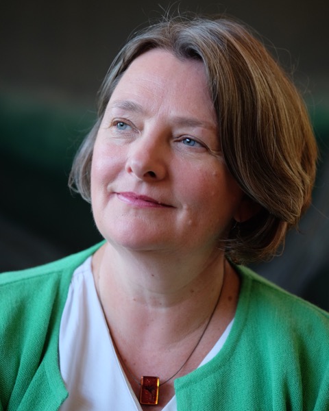 Headshot of Stephanie Cairns. She's looking thoughtfully off to the side, has chin-length brown hair, and is wearing a white shirt with green cardigan.