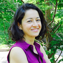 woman with dark hair and purple blouse smiling