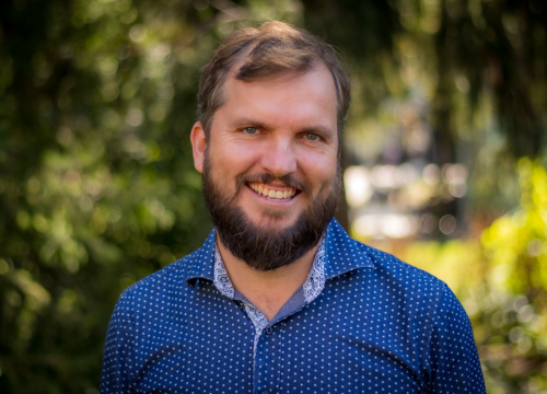 Mervyn Horgan stands outside and smiles at the camera, wearing a blue polo shirt.