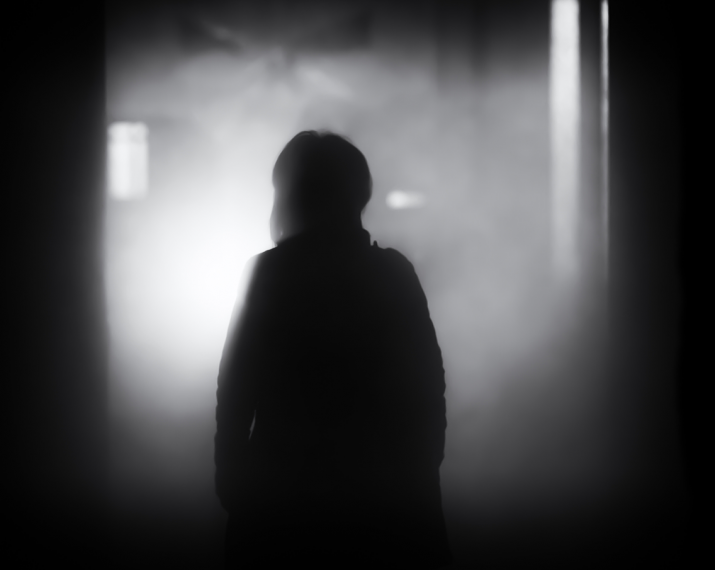 woman basked in shadow, standing in a dark alley.