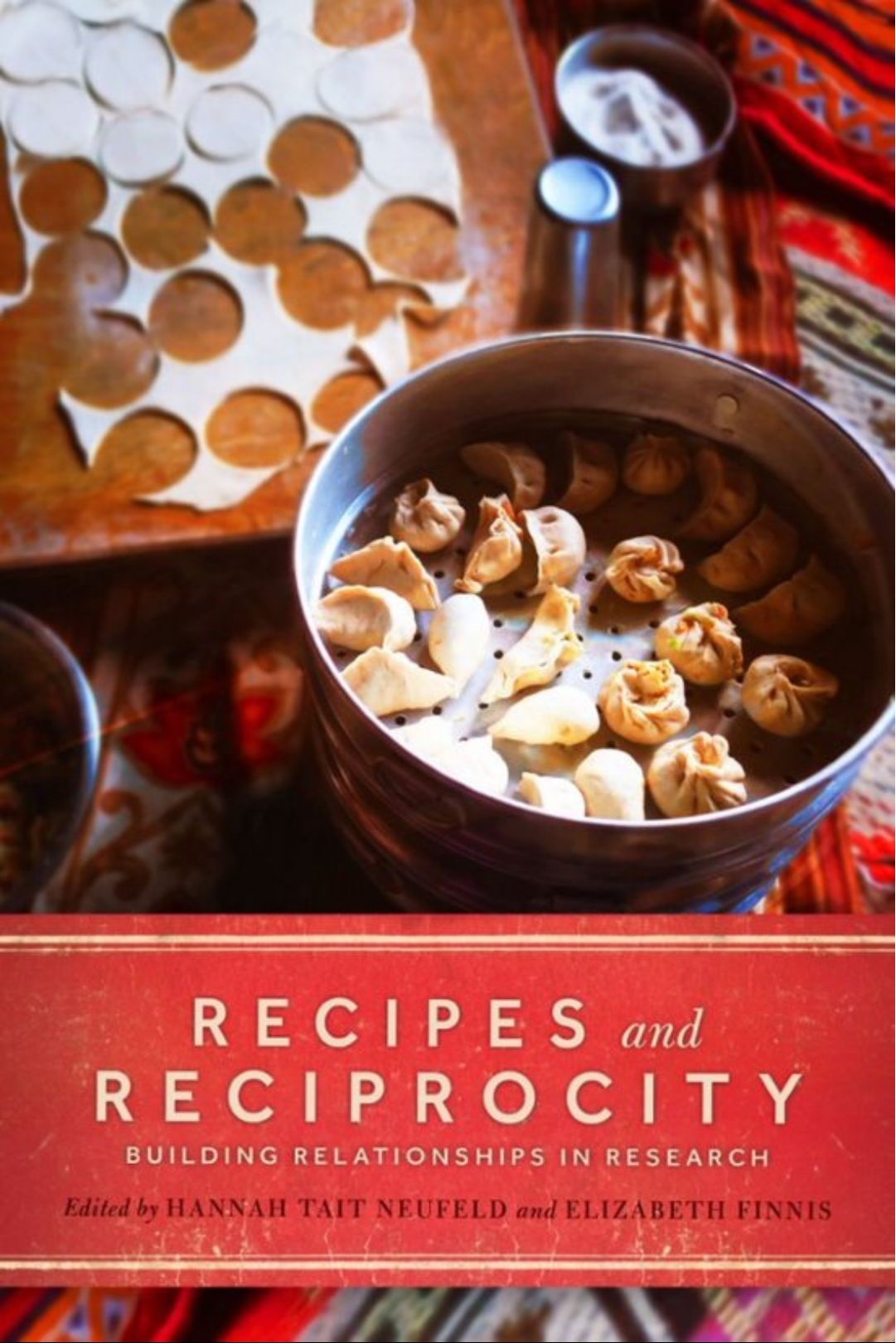 The cover of Recipes and Reciprocities, which features a photo of dumplings sitting in a steamer beside rolled out dumpling dough that's been cut into.