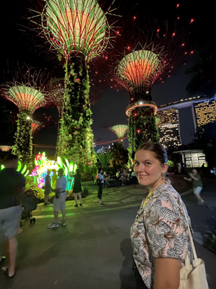 Alara looking back over her shoulder at the camera, behind her large tree-like structures lit up against the night sky.
