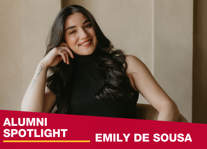 Photo of Emily De Sousa sitting on chair leaning on her hand smiling. 