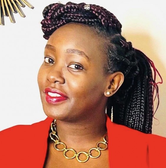 Laureen Owaga headshot. Laureen has her hair pulled back in braids and is wearing a red blazer with a necklace and dangling earrings.