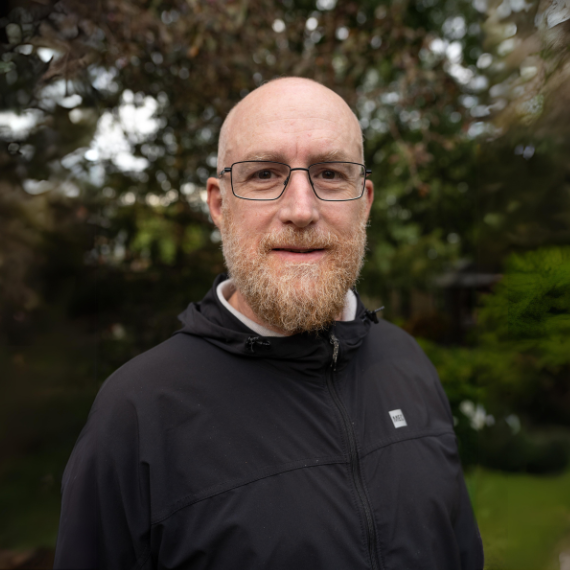 Tad McIlwraith stands outdoors posing for a photo.