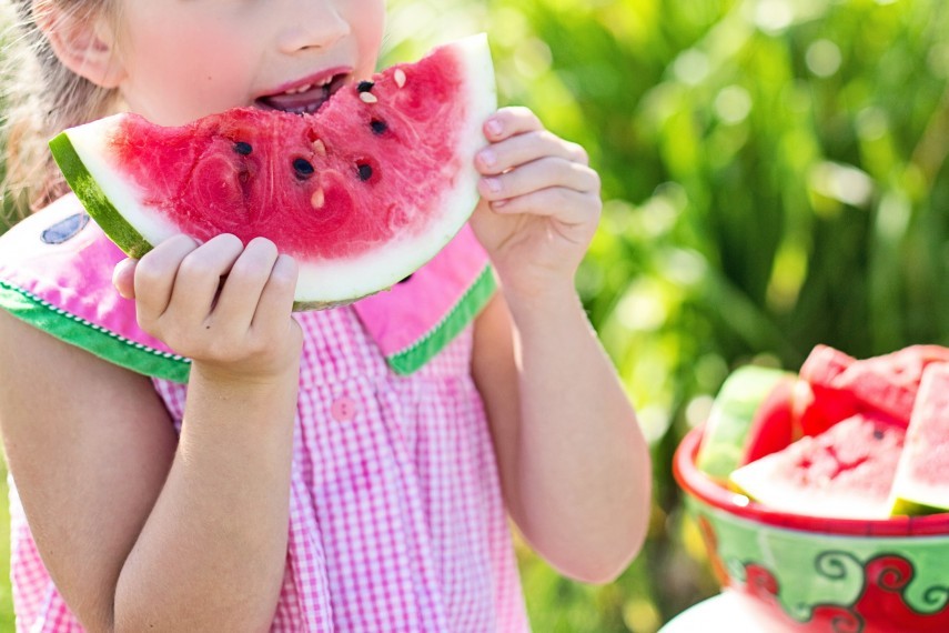Young girl eating watermelon outside on sunny day