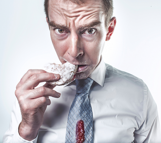 upset man eating a jelly donut with jelly on his tie