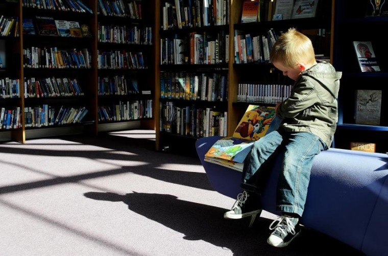 Image of child sitting in library reading a book